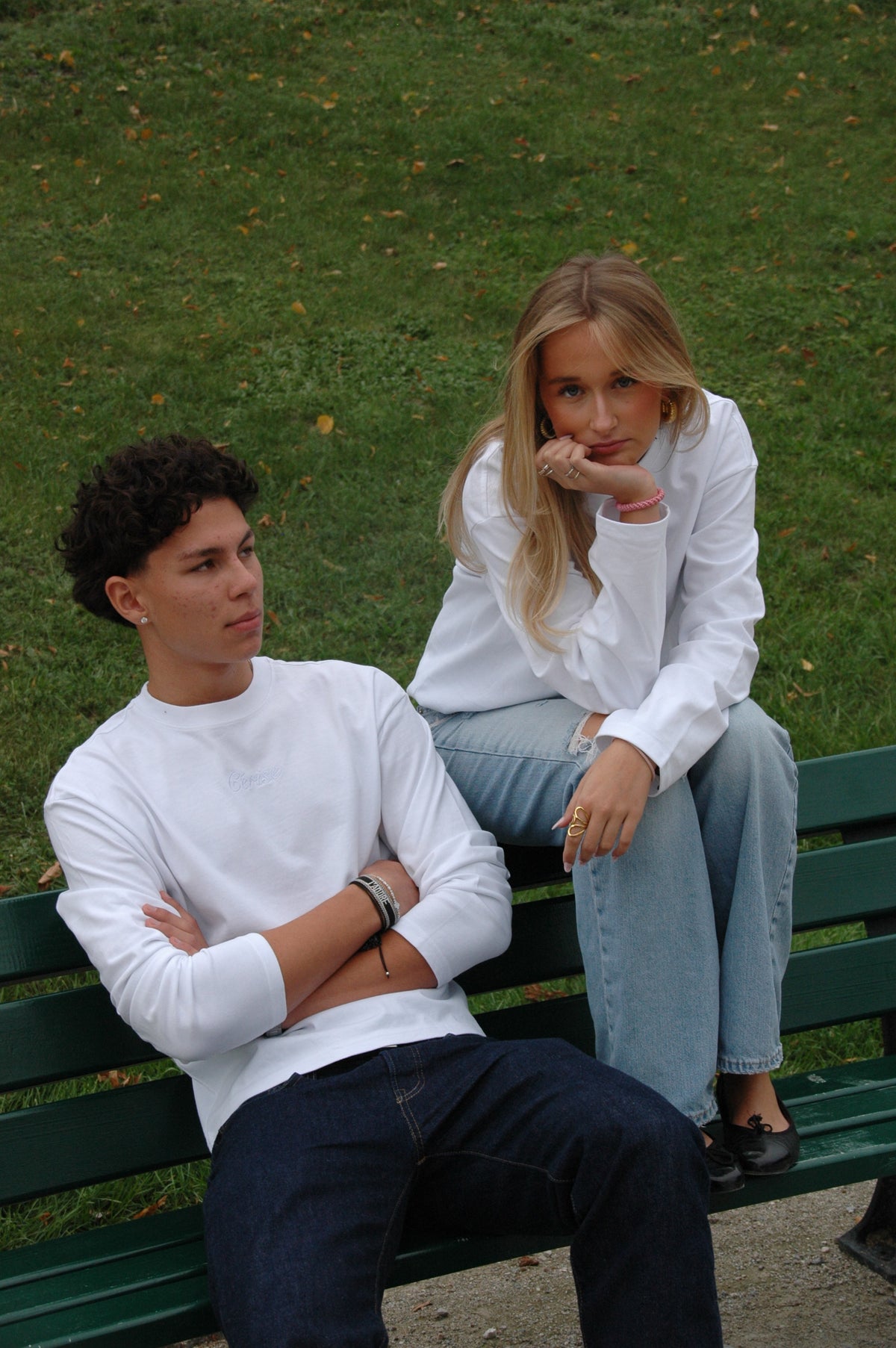 Zwei Models in weißen Cérise Langarmshirts Blanc auf einer grünen Parkbank