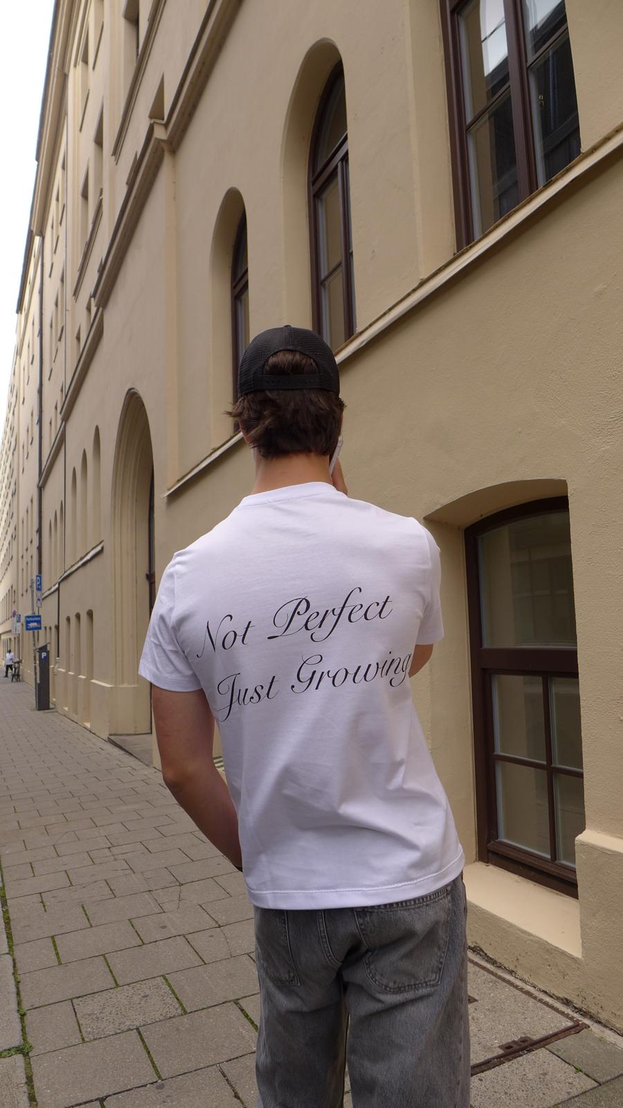 Rückansicht eines Models im weißen Cérise T-Shirt mit dem Schriftzug Not Perfect Just Growing